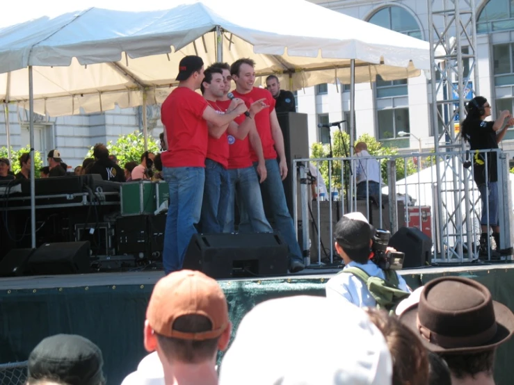 the guys are standing on top of a stage