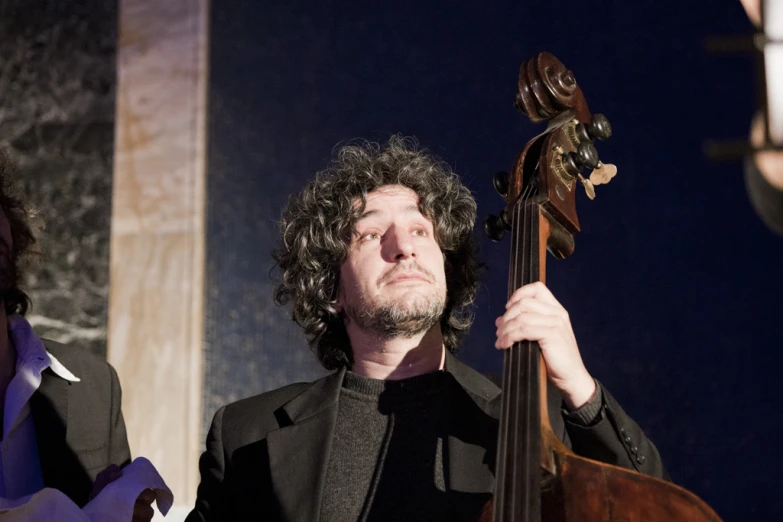 a man in a black suit holding his cello