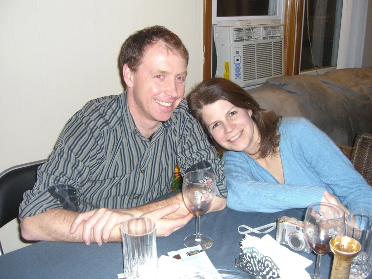 a man and woman sitting at table with glasses of wine