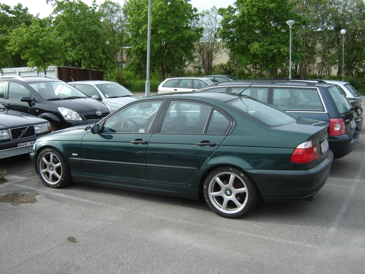 a green bmw sits in the parking lot