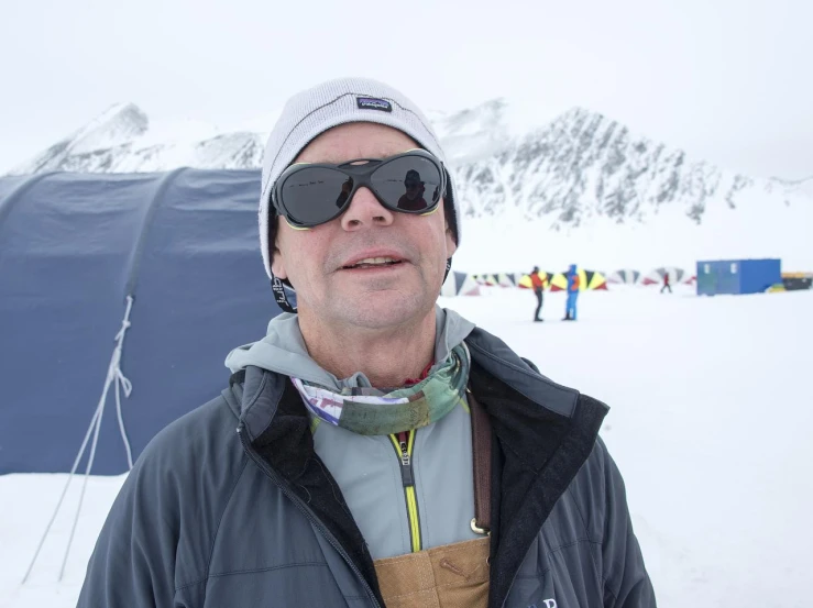 a man wearing sunglasses while standing in the snow