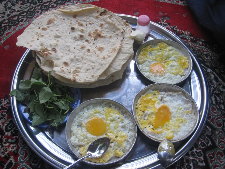 three plates of food with a flat bread and eggs on it