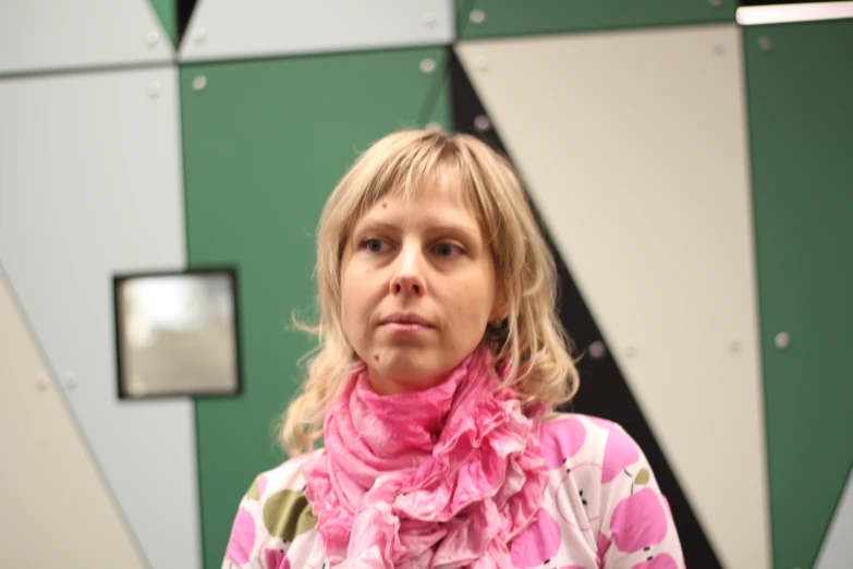 a lady with pink scarf in front of wall