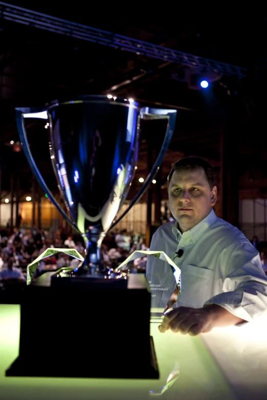 the man poses next to the trophy at an event