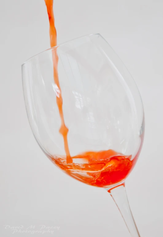 orange colored liquid pouring into a wine glass