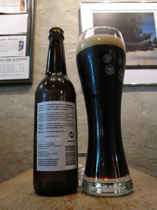 a dark beer in a glass on top of a wooden table