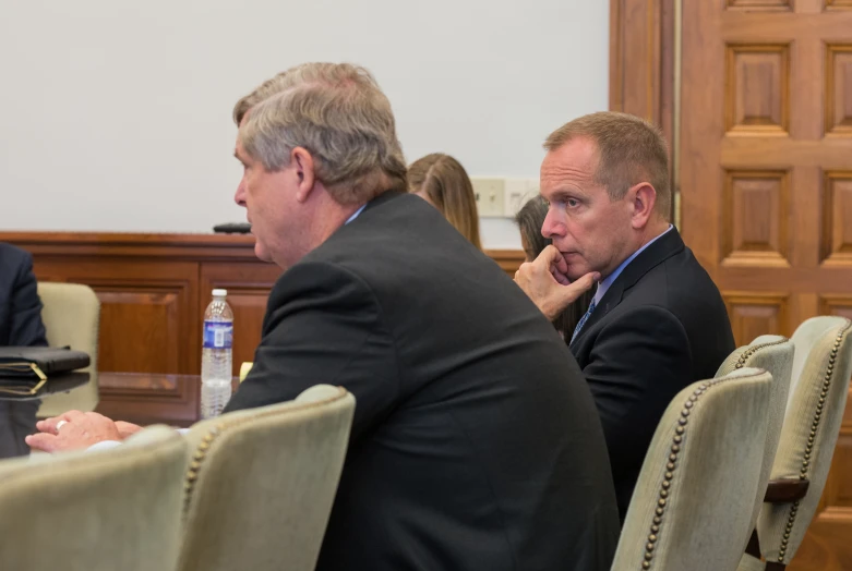 four men sitting at a table, one is talking