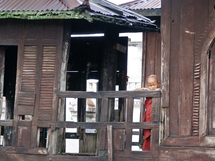 a little boy on the balcony in his hut looking out