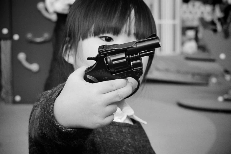 a girl wearing a jacket and holding a black handgun