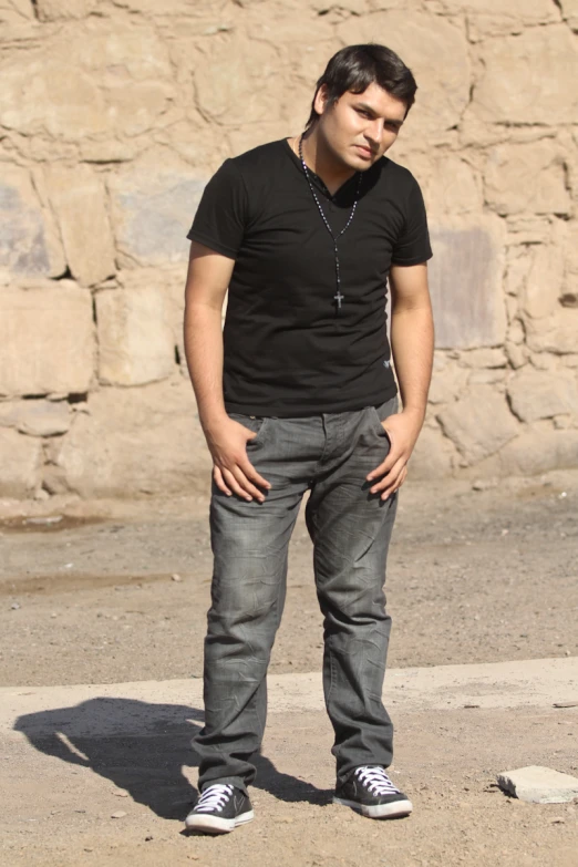 a man standing on the pavement near a stone wall