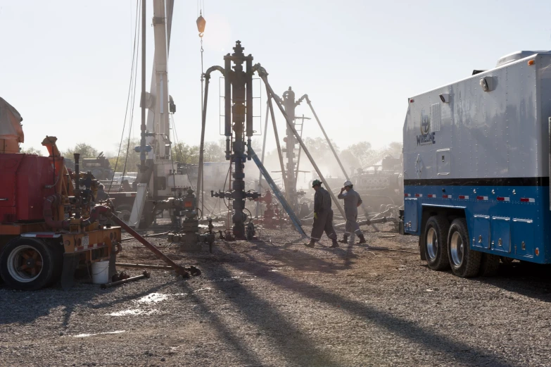 a couple of men standing in front of a drilling rig