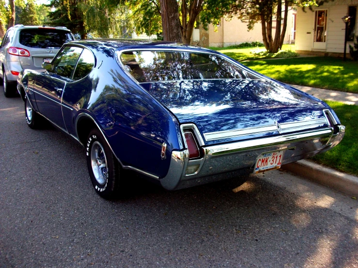 a blue pontiac coupe on a suburban street