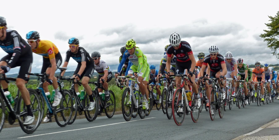 a large group of cyclists riding down a paved road