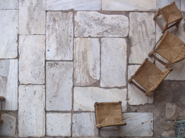 the two chairs and the one chair are set near an empty space with rocks and whitewashed walls