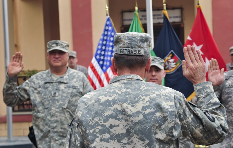 a group of military men stand in front of flags and the colors