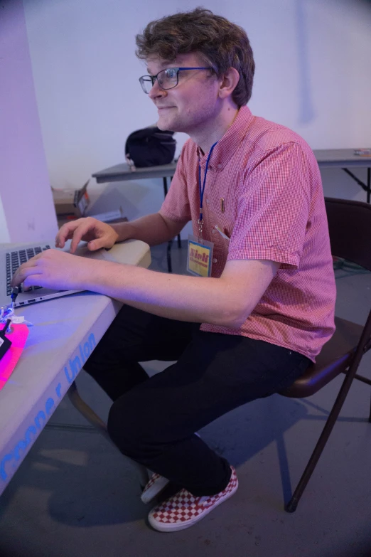 a guy sitting in front of a laptop with the keyboard lit up