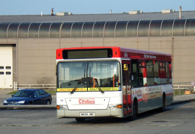 a passenger bus sits on the street in front of a building