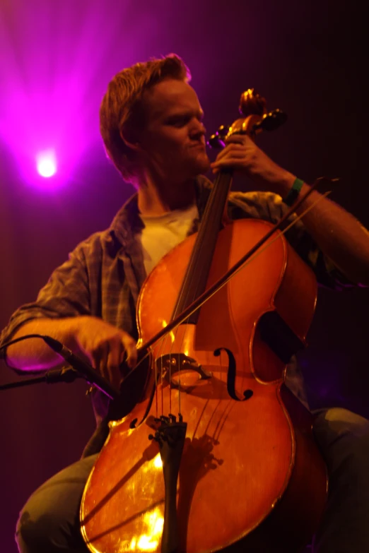 man sitting on chair while playing violin in concert