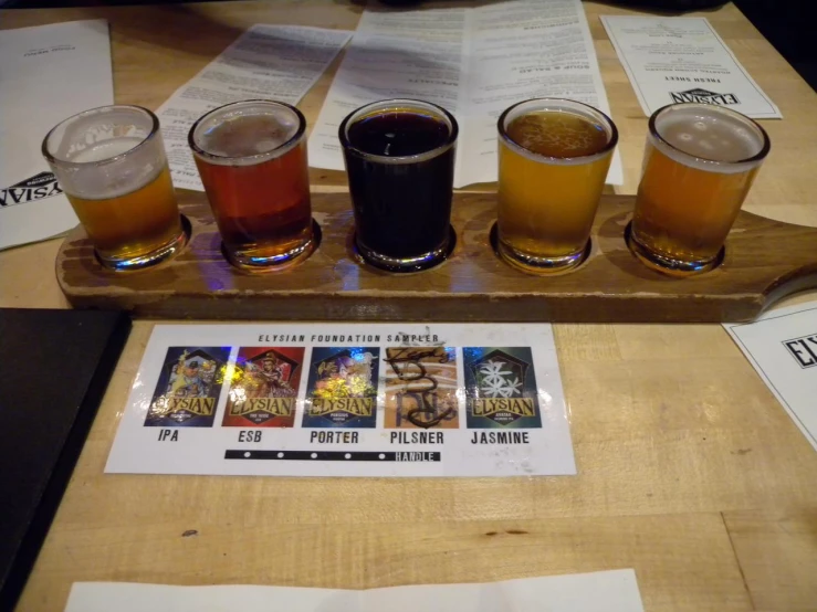 a wooden tray on the table with six different beers in it