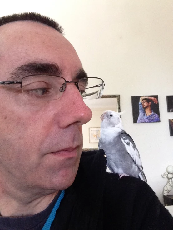 a man in glasses standing next to a parrot