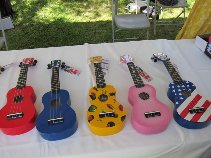 a number of colorful ukuleles laying on a table