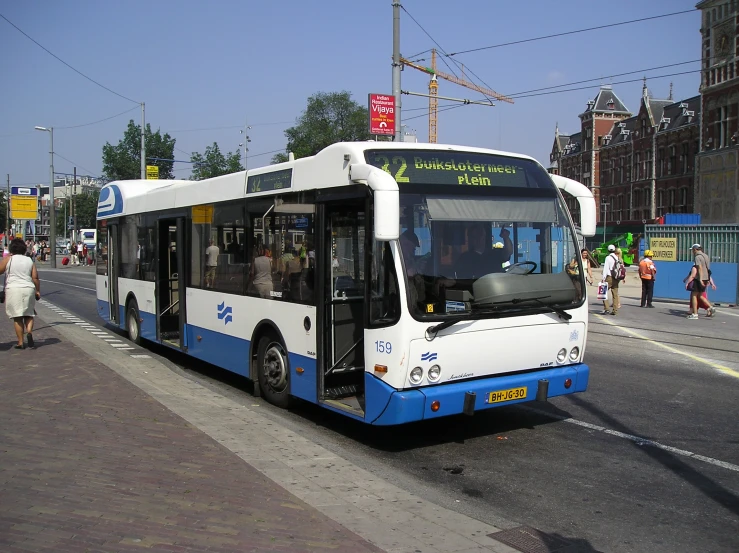 people walk on a street near a parked bus