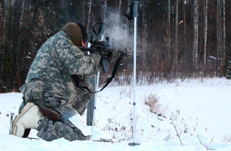 a man wearing camouflage standing near a street light with a camera in hand