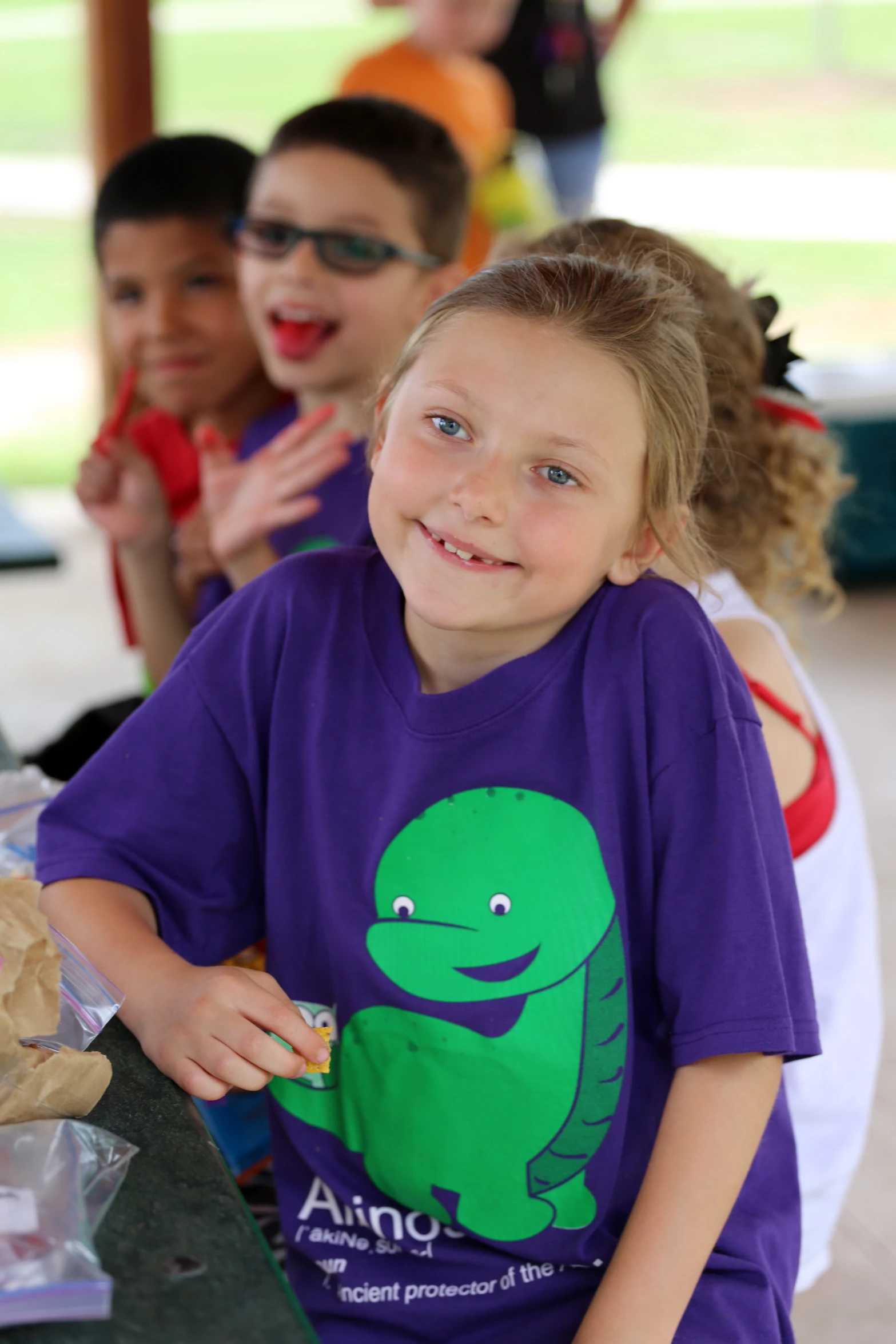 a little girl sitting next to two other girls