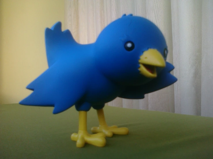 a blue bird with its mouth open on a table