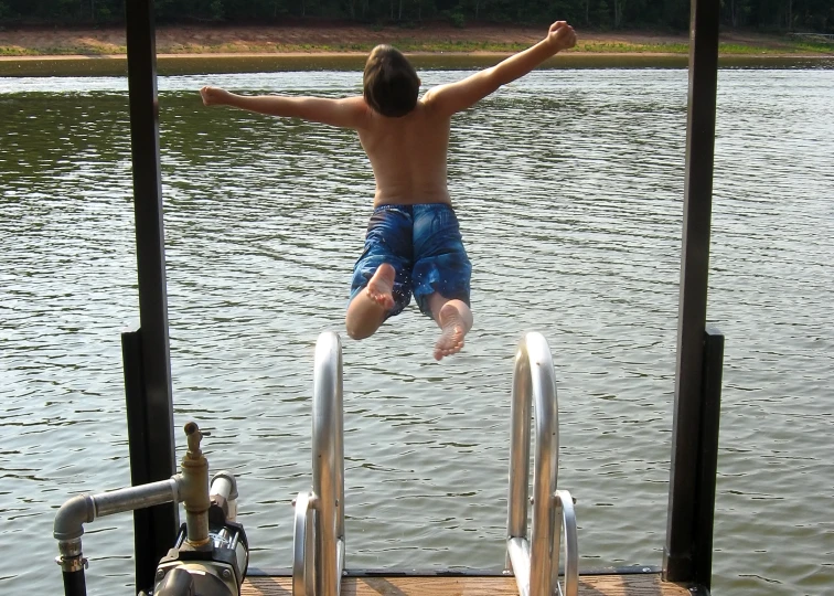 a man jumping off the edge of a pier into the water