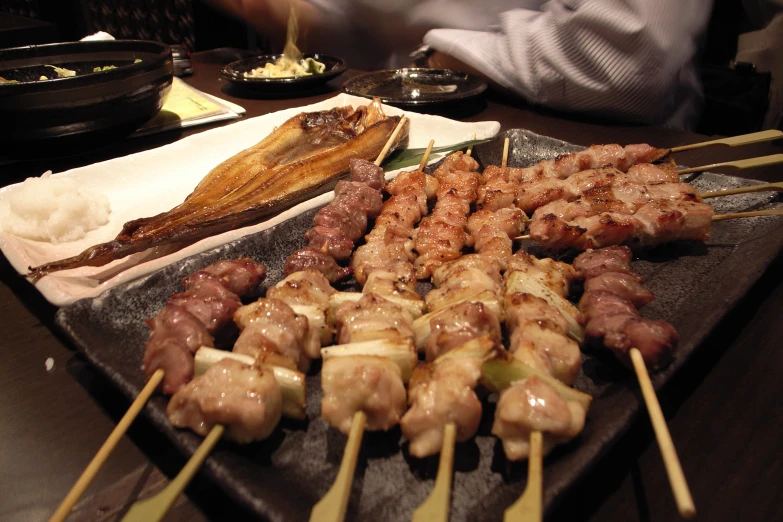 several meats and skewers are served on a tray