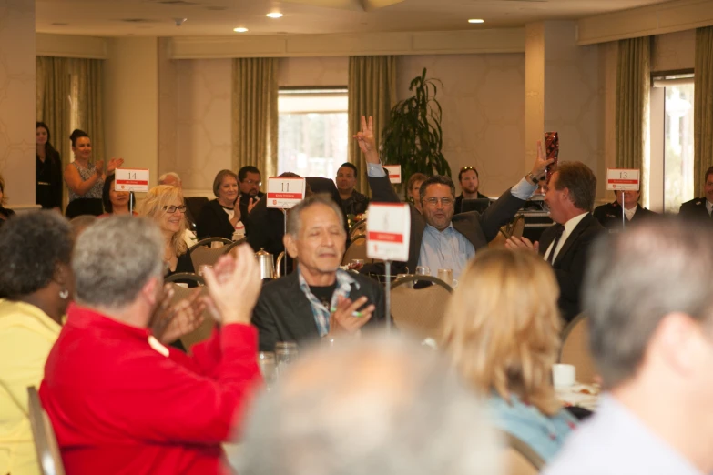 an audience in a room listening to a man giving a presentation