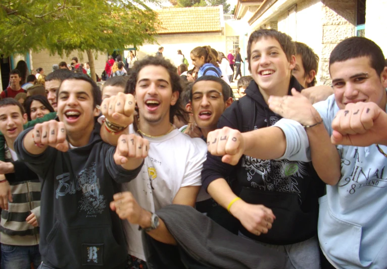 young men and one man wearing wrist bands giving the middle finger sign