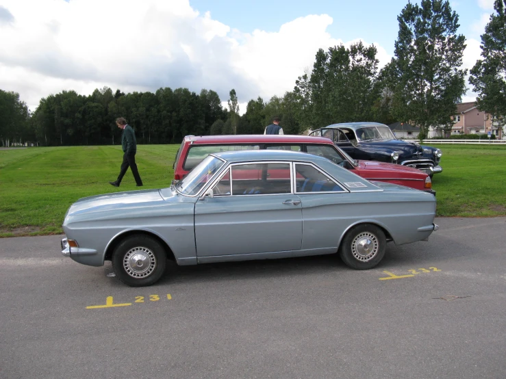 two classic cars are parked on the street in front of someone