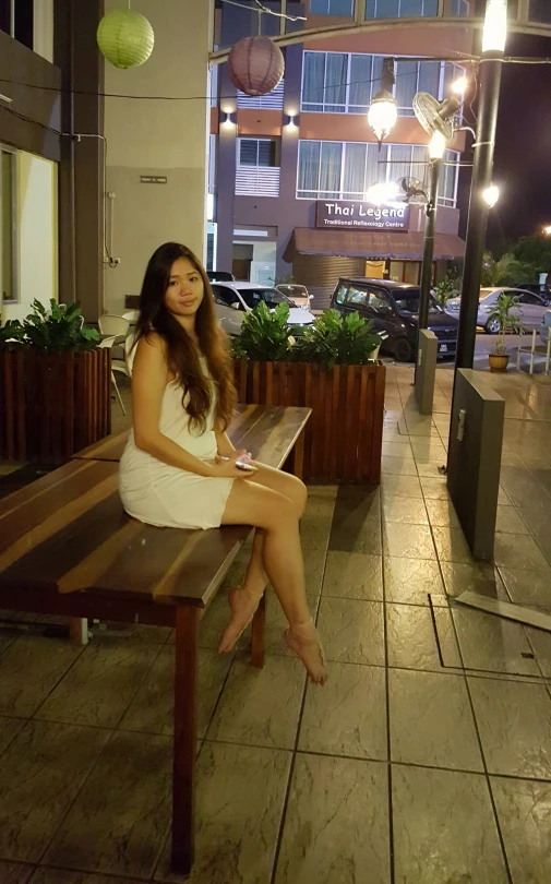 a woman wearing white sitting on a wooden bench