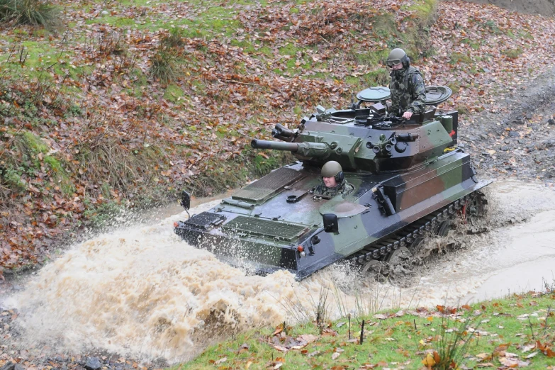 a tank driving through a flooded creek in the rain