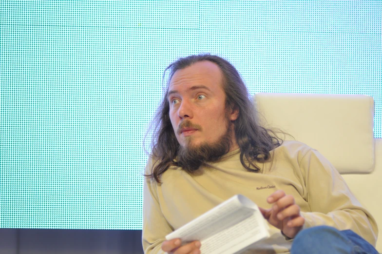 a man sitting down reading some paper with a surprised look on his face