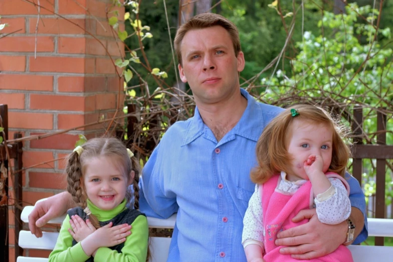 two little girls and a man are on a bench