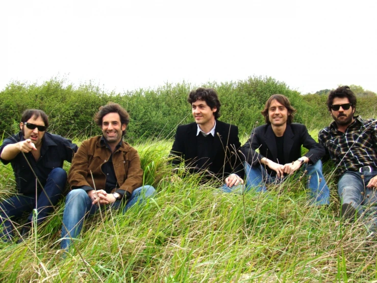 a group of men sitting on the grass near each other