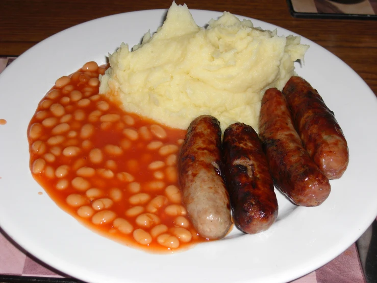 a plate topped with baked beans, mashed potatoes and sausage
