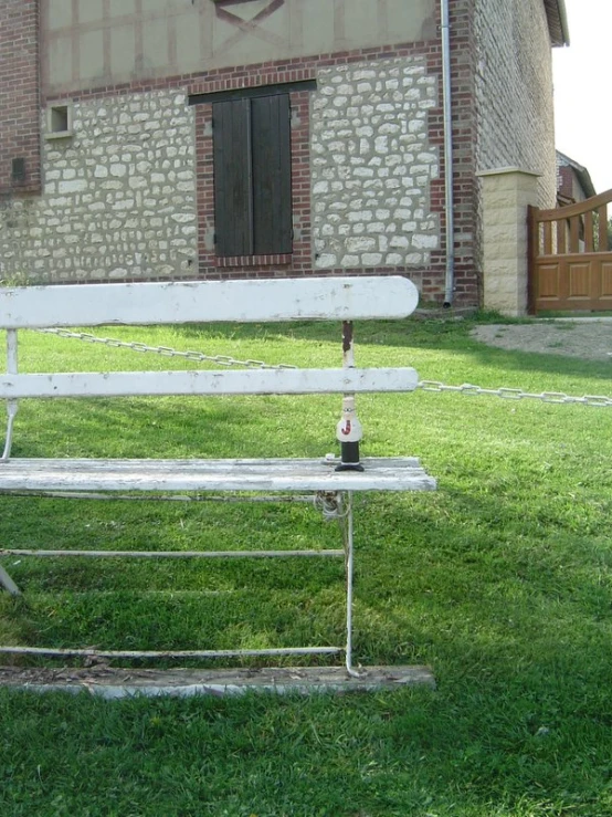 white bench sitting in the grass next to a building