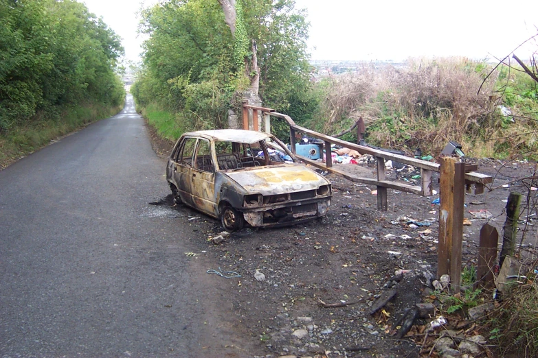 the rusty car is parked on the side of the road