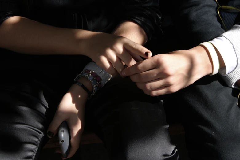 the hands of two people holding cell phones with their hands together