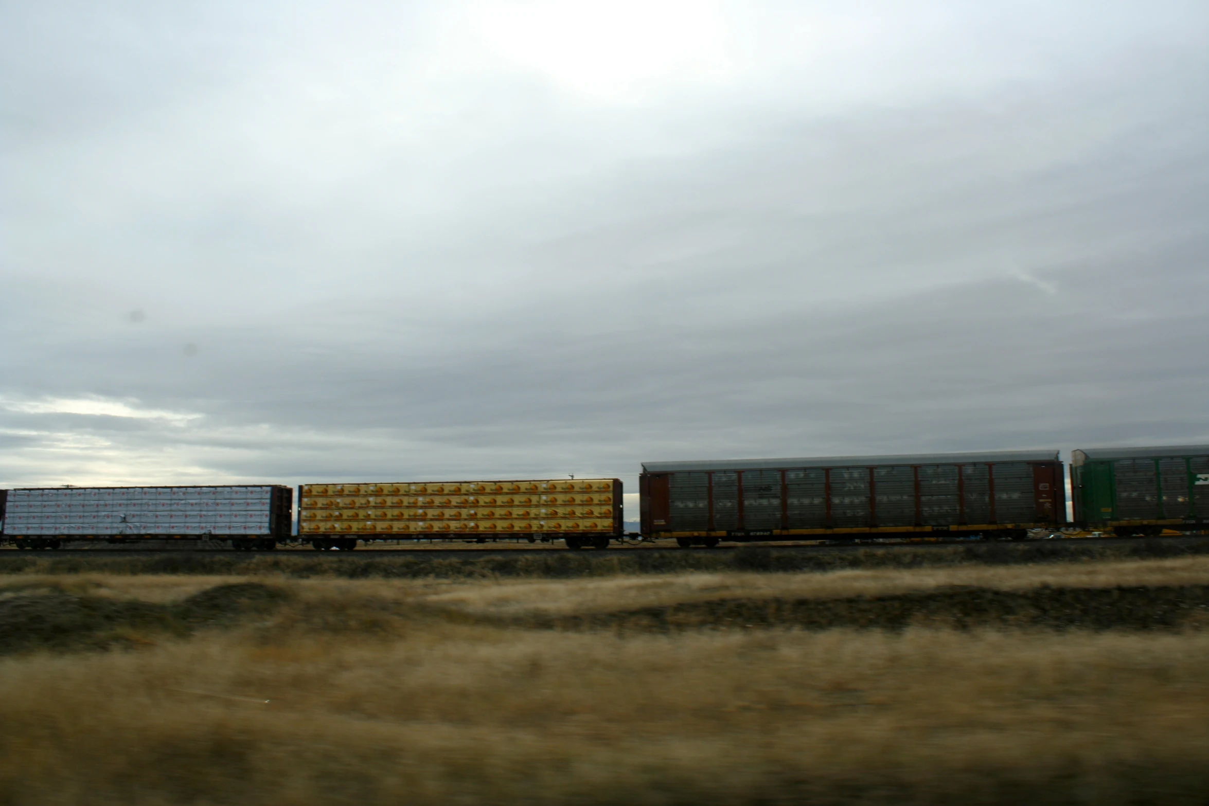 train cars traveling down tracks during cloudy day