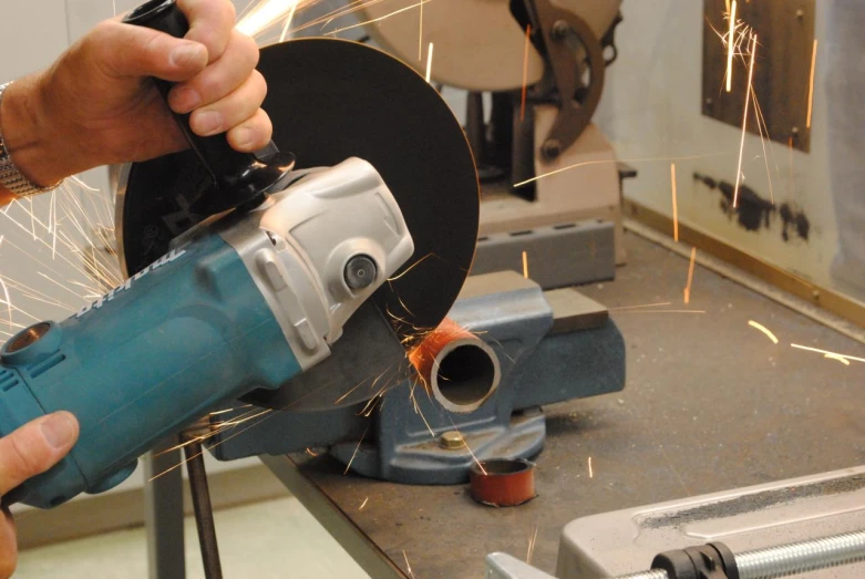 man using a grinder with metal blades in the foreground