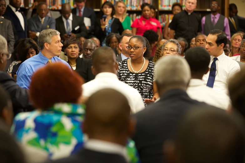 a woman in a black and white dress is talking to a large group of people