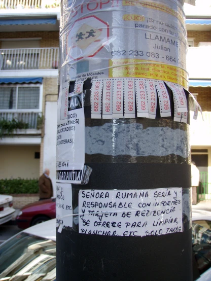 many stickers attached to a street pole on the road