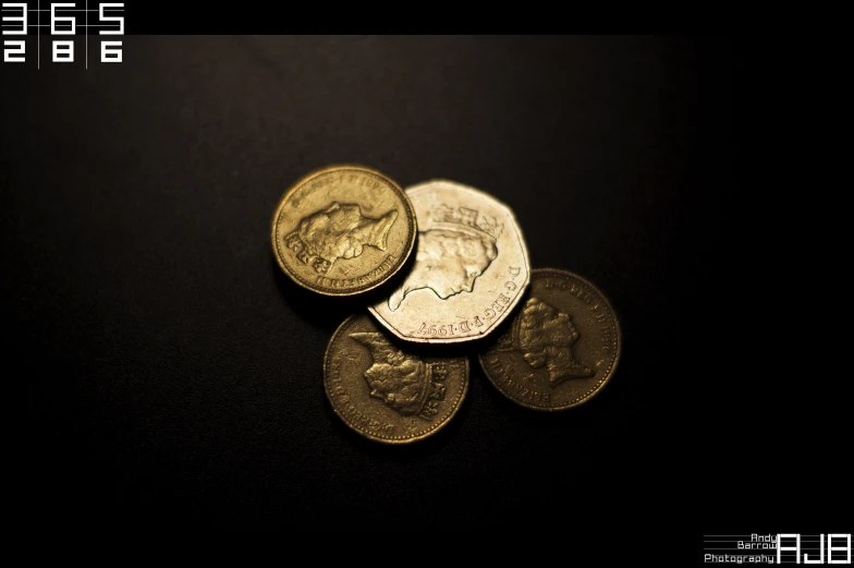 five gold coins on a black surface