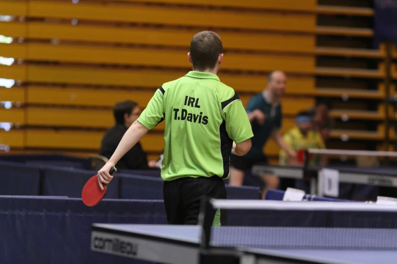 man in green shirt playing with ping pong paddle