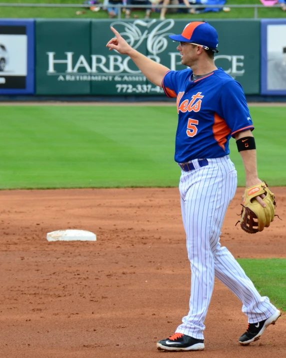 a baseball player pointing to soing while standing on a baseball field